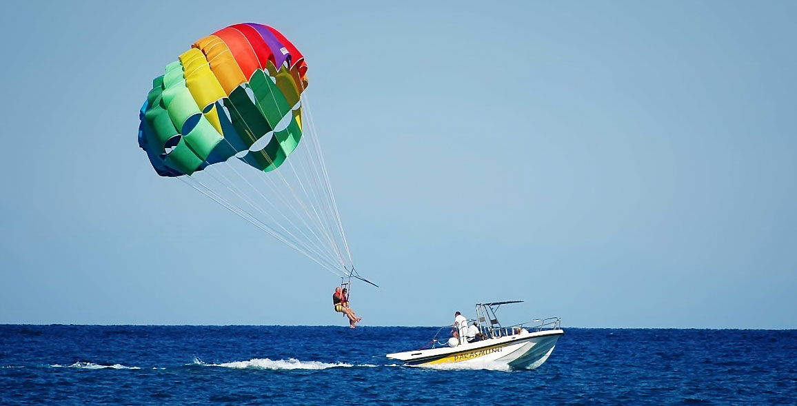 Family experiencing adventurous parasailing through the sky while towing behind a yacht near Jumeirah Beach in Dubai